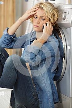 unhappy woman showing signs fatigue near washing machine