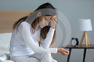 Unhappy woman sitting on bed, feeling depressed, thinking about problems