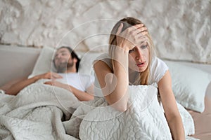 Unhappy woman sitting on bed, suffering from her boyfriend& x27;s snoring, feeling dissatisfied because of sexual