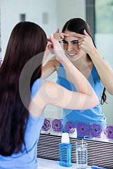 Unhappy woman with skin irritation cleaning her face