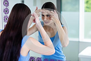 Unhappy woman with skin irritation cleaning her face