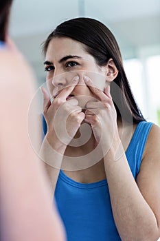 Unhappy woman with skin irritation cleaning her face