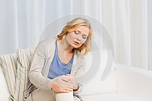 Unhappy woman suffering from pain in leg at home