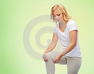 Unhappy woman suffering from pain in leg at home