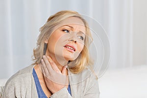 Unhappy woman suffering from throat pain at home