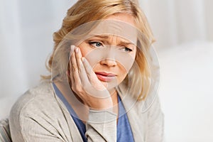 Unhappy woman suffering toothache at home