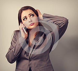 Unhappy worried business woman talking on mobile phone and looking up. Toned vintage portrait