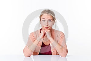 Unhappy young blond woman sitting, apologizing and feeling sorry