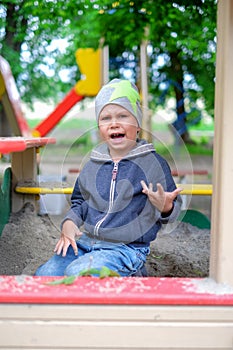 Unhappy Young boy playing in the sandbox