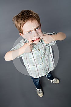 Unhappy young boy standing with big mouth for determined attitude