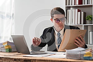 Unhappy young businessman feeling bored and stressed at work looking at laptop with hopeless expression while sitting in