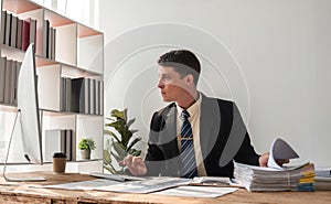 Unhappy young businessman feeling bored and stressed at work looking at laptop with hopeless expression while sitting in