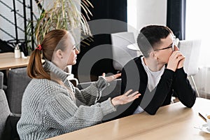 Unhappy young couple arguing, angry wife looking at husband blaming him of problems, conflicts in marriage, bad