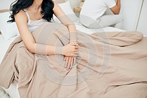 Unhappy Young Couple Sitting On Bed In Bedroom