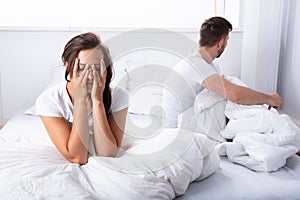 Unhappy Couple Sitting On Bed