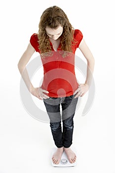 Unhappy Young Girl Standing On Scales