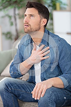 unhappy young man suffering from panic attack at home