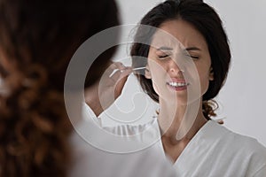 Unhappy young woman feeling pain cleaning ears.