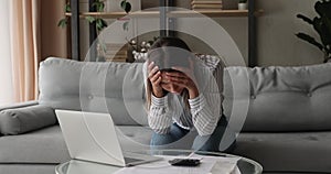 Unhappy young woman feeling stressed doing financial paperwork.