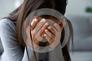 Unhappy young woman hiding face in hands, feeling desperate.