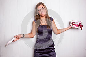 Unhappy young woman holding gift box