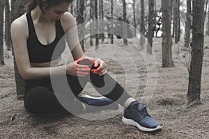 Unhappy young woman sitting in the garden, grabbing an ankle, un