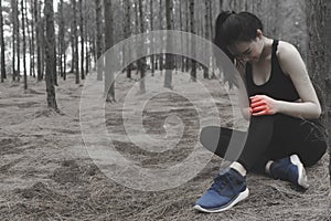 Unhappy young woman sitting in the garden, grabbing an ankle, un