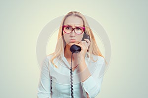 Unhappy young woman talking on mobile phone looking down