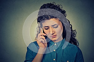 Unhappy young woman talking on mobile phone looking down