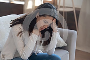 Unhappy young woman touching forehead, thinking about relationship problems