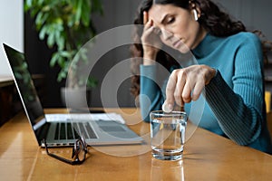 Unhealthy businesswoman taking painkiller from headache or migraine at workplace in office