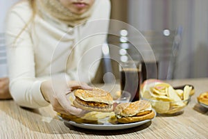 Unhealthy concept. The girl is sitting at the table and eating