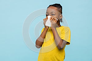 Unhealthy dark- skinned little boy suffering runny nose