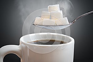 Unhealthy eating concept. Many sugar cubes above hot cup of tea or coffee