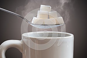 Unhealthy eating concept. Many sugar cubes above hot cup of tea or coffee
