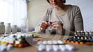 Unhealthy elderly lady drinking pills, vitamins, illness symptoms, hypochondria photo