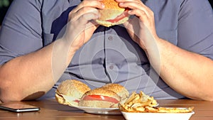 Unhealthy food addiction, obese hungry man eating fatty burgers, overweight