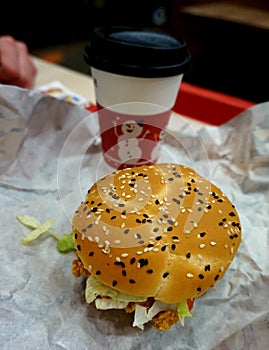 Unhealthy food: a hamburger and coffee in a paper cup.