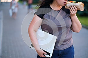 Unhealthy food at lunchtime, girl eating on the go