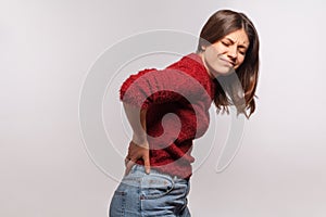 Unhealthy girl in shaggy sweater touching sore back, feeling acute pain, suffering kidney inflammation photo