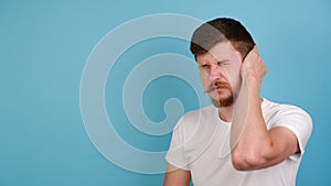 Unhealthy guy suffering from strong earache. Unhappy young man plugging ear, feeling painful discomfort, avoids bad sound