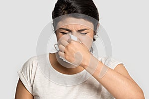 Unhealthy indian young girl using paper tissue cleaning runny nose.