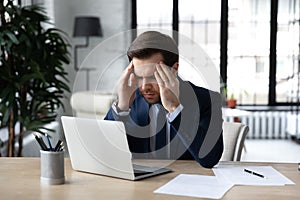 Unhealthy male employee struggle with headache at workplace