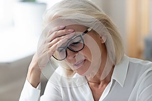 Unhealthy mature female suffer from headache at workplace photo