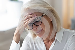 Unhealthy mature female suffer from headache at workplace