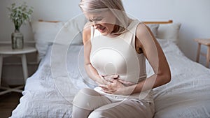 Unhealthy mature woman holding belly, suffering from pain photo