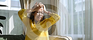 Unhealthy mature woman touching her head suffering from headache, migraine or dizziness. Age, medicine, health care and