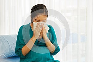 An unhealthy pregnant woman causes complications of the common cold, holding a tissue over her nose.