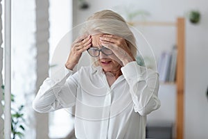 Unhealthy senior female employee suffer from headache