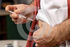 Unhealthy unrecognizable man with syringe making insulin injection by himself